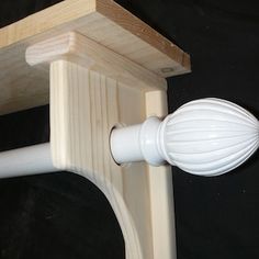 a close up of a white plastic object on a wooden stand with a black background