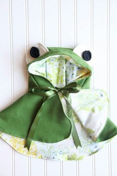 a green frog hat and bib on a white wall