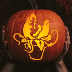 a person holding up a carved pumpkin with an image of a dog on it