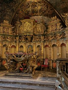 an ornately decorated church with gold and red decorations on the walls, pews and chairs