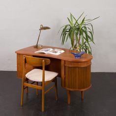 a wooden desk with a chair next to it and a potted plant on top