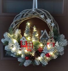 a wreath with christmas decorations and lights hanging from the front door to look like a village