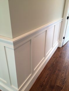 an empty room with hard wood floors and white paneling