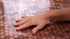 a person's hand on top of a table covered in pennets and coins