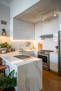 a kitchen with white cabinets and marble counter tops, stainless steel appliances and an island