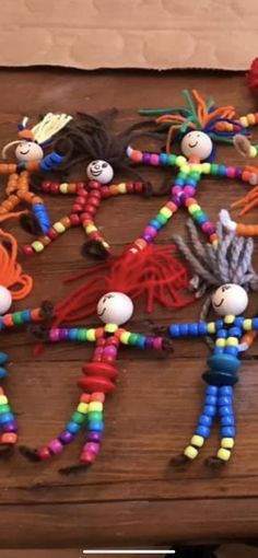 several colorful beaded dolls are arranged on a wooden table