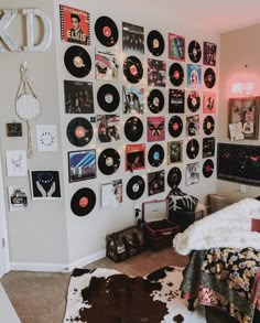 a bedroom with records on the wall and cow hide rugs in front of it