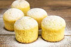 four yellow muffins sitting on top of a wooden table