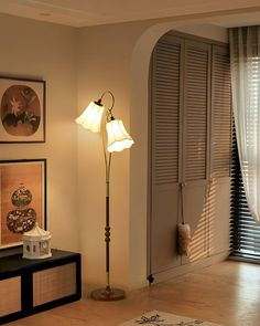 a living room with a lamp and pictures on the wall next to an open door