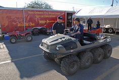 two police officers riding on four wheelers in a parking lot next to other vehicles