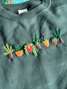 a green sweater with embroidered plants on it