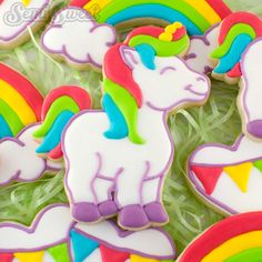 decorated cookies in the shape of unicorns and rainbows are on display with grass