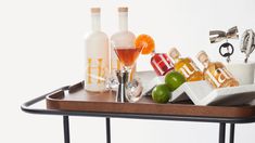 a tray with bottles and glasses sitting on top of a table next to an orange slice