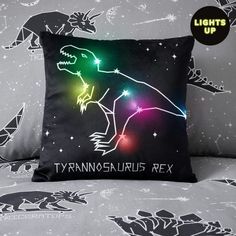 a pillow that has a dinosaur on it with lights up in the sky behind it