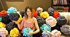 a woman is sitting on the floor surrounded by giant braided pillows and holding a baby