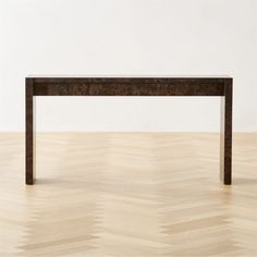 a wooden table sitting on top of a hard wood floor next to a white wall