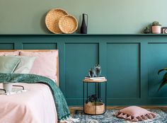 a bedroom with teal walls and pink bedspread, two planters on the wall