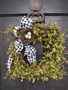 a wreath on the front door with an egg in it and some greenery around it