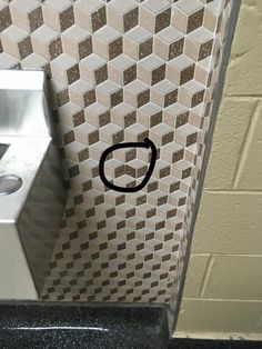 a bathroom stall with a black circle drawn on the wall next to a toilet paper dispenser