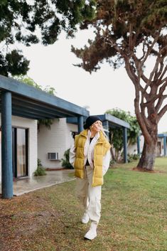 a person standing in front of a tree with their eyes closed and wearing a yellow jacket