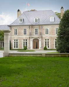 a large brick house sitting on top of a lush green field