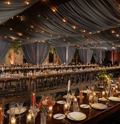 a large banquet hall with tables and chairs covered in white draping, lit by candles