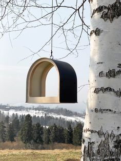 a bird feeder hanging from the side of a tree in front of a snowy landscape