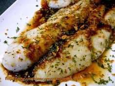 two fish fillets on a white plate covered in sauce