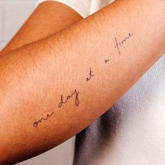 a person with a tattoo on their arm that says, one day at a time