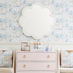 a dresser and mirror in a room with floral wallpaper on the walls behind it