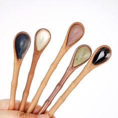 five wooden spoons with different colors and shapes in the palm of a person's hand