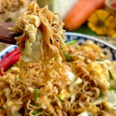 a spoon full of noodles and vegetables in a bowl