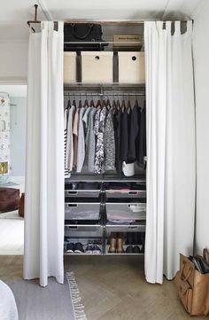 an open closet with white curtains and clothes