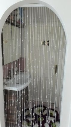 an arched window with raindrops on the glass and white curtains hanging from it