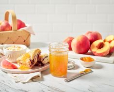 a table topped with plates and bowls filled with food next to peaches on top of a white counter