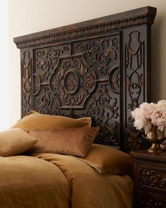 the headboard is made up with intricate carvings and gold linens, along with pillows