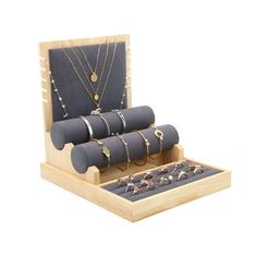 a set of jewelry in a wooden box with necklaces and rings on the tray