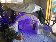 a room decorated for christmas with lights and decorations on the windowsill, including a bed covered in white fabric