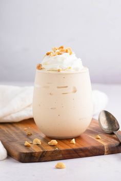 a dessert in a glass with whipped cream and walnuts on a cutting board next to a spoon