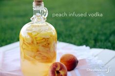 a glass bottle filled with liquid next to two peaches