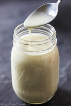 a spoon is pouring milk into a jar