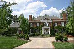 a large brick house surrounded by lush green trees