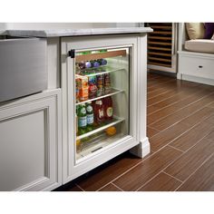 an open refrigerator with drinks in it sitting on the floor next to a counter top