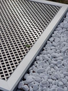 a metal grate sitting on top of a pile of rocks next to a green plant