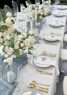 the table is set with silverware and white flowers