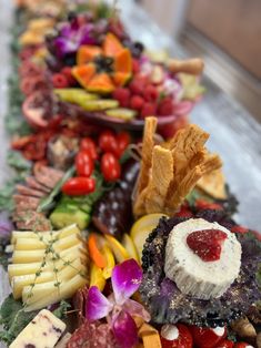 an assortment of fruits and veggies are arranged on a long platter with crackers