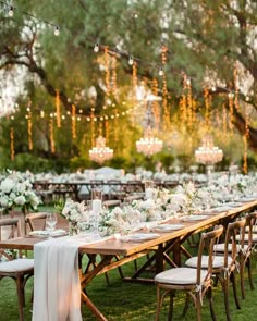 a long table with white flowers and candles is set up for an outdoor wedding reception