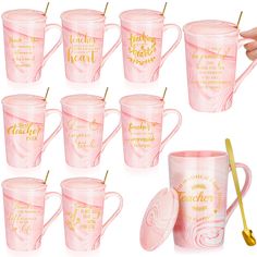 a set of twelve pink coffee mugs with gold lettering on the side and spoon