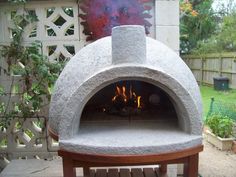 an outdoor pizza oven sitting on top of a wooden table