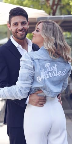 a man and woman in white pants hugging each other